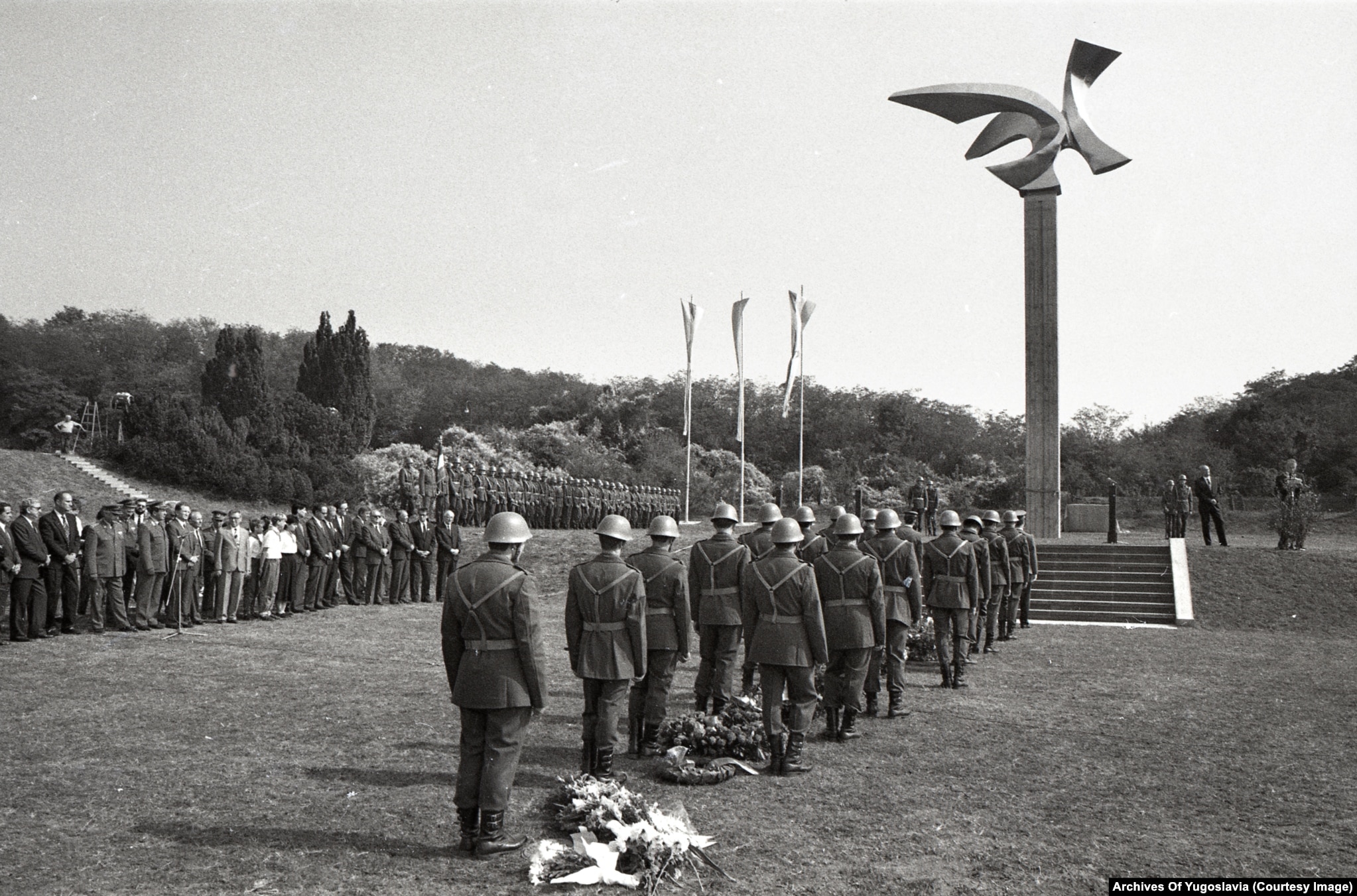 Rows of seated guests and speakers at a podium during the Jajinci Memorial Park opening in Belgrade, October 1989.