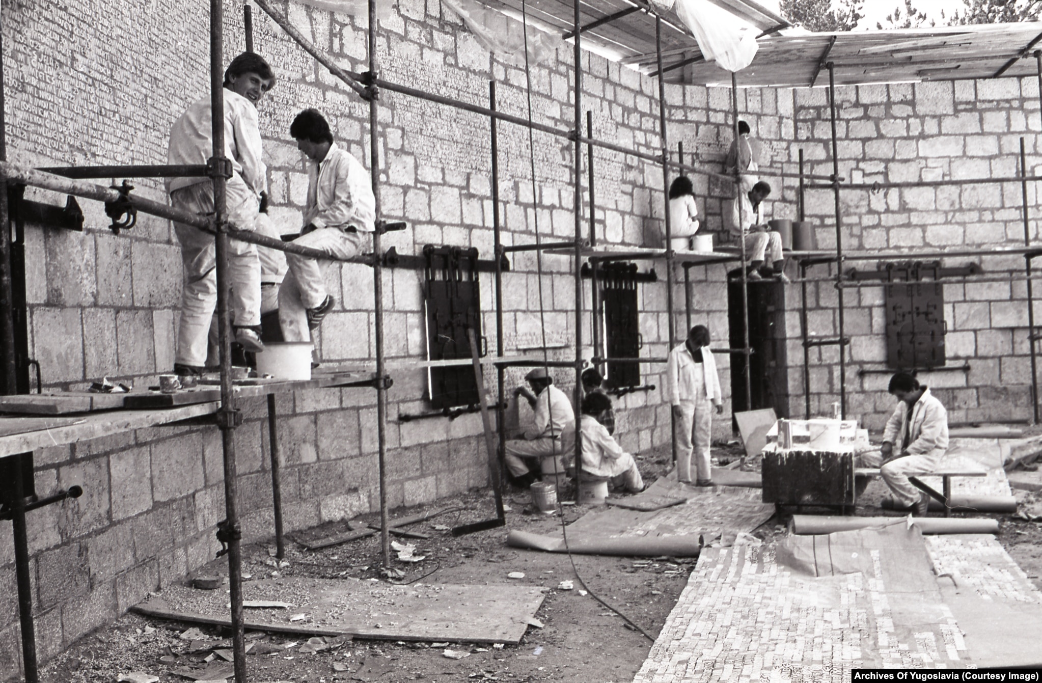 Workers chiselling lettered name plates into stone blocks on a hillside memorial terrace at Vraca, 1981.
